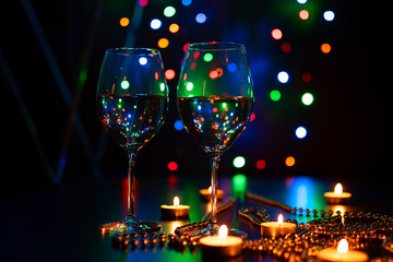 Two wine glasses and Fire of candle on christmas background. Christmas candles burning at night. Abstract candles background. Golden light of candle flame. Hope, fire. Candle lights in the darkness.