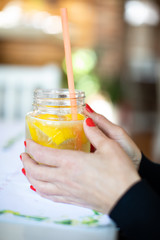 Fototapeta premium lemon juice with woman hands with red manicure
