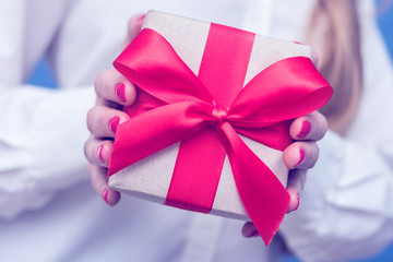 Woman holding a box with a gift, red ribbon, front view, close up, toned, cropped image
