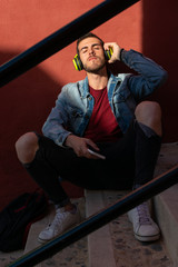 Outdoor portrait of modern young man with smart phone sitting in the street