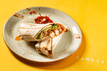 Burritos wraps with chicken and vegetables on yellow background