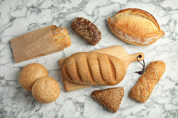 Different kinds of fresh bread on marble table, flat lay