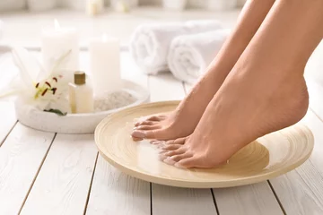 Foto op Canvas Closeup view of woman soaking her feet in dish with water on wooden floor, space for text. Spa treatment © New Africa