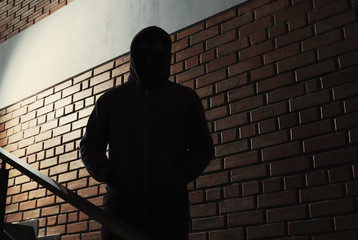 Silhouette of mysterious man in hoodie indoors. Dangerous criminal - obrazy, fototapety, plakaty