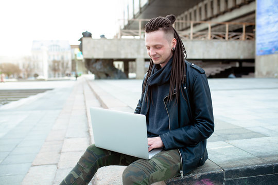 Young man sitting on the stairs using laptop