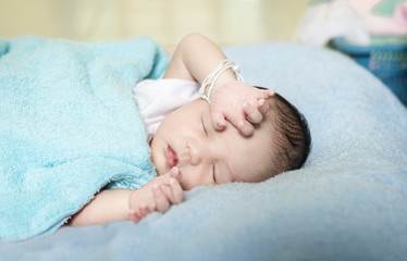  Asian little baby sleeping on a blue blanket in bedroom . Asian Infant nappy change after bath or shower. close up Happy adorable asian baby on the bed