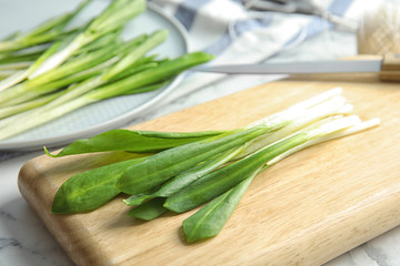 Board with wild garlic or ramson on table, closeup