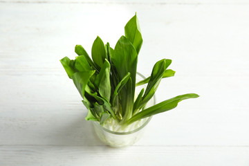 Glass of wild garlic or ramson on white wooden table, above view
