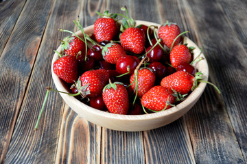 Strawberries and cherries in a brown wooden bowl. Fresh organic summer berries