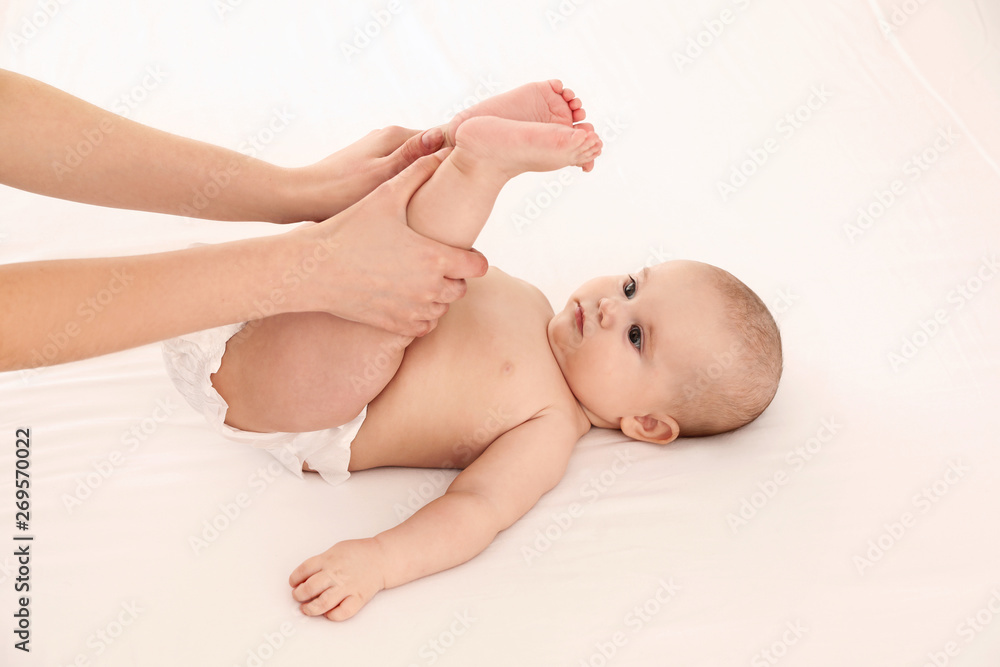 Sticker Mother and her cute child on white bed. Baby massage and exercises