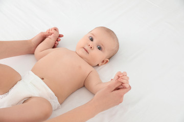 Mother and her cute child on white bed, space for text. Baby massage and exercises
