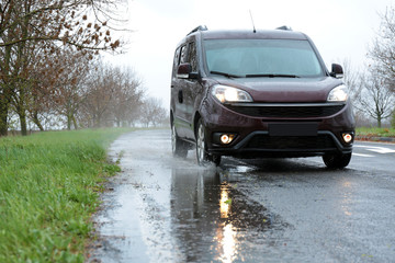 Fototapeta na wymiar Wet suburban road with car on rainy day