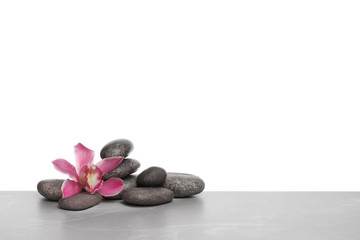 Fototapeta na wymiar Orchid flower with spa stones on white background. Space for text