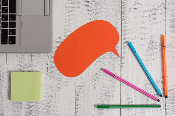 Open laptop speech bubble ballpoints sticky notes vintage wooden table