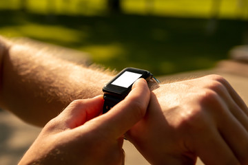 Man clicking on a button of his smart watch on sunset