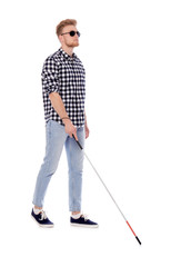 Young blind person with long cane walking on white background