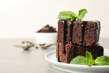 Fresh brownies with sauce and mint on table, space for text. Delicious chocolate pie