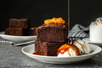 Pouring sauce onto ice-cream with fresh brownies on plate. Delicious chocolate pie