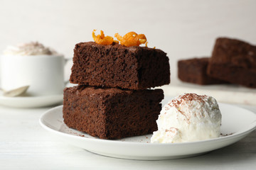 Plate with fresh brownies and ice-cream on table. Delicious chocolate pie