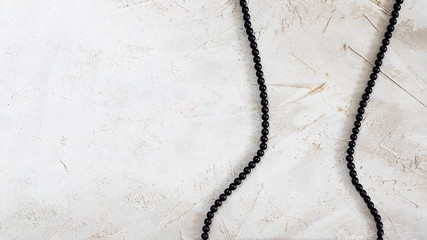 Black bijouterie bead lace as woman waist on grey textured cement surface, Horizontal with copy...