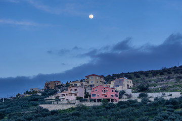 Archanes, Crete Island / Greece. Full moon above Archanes village in the perfecture of Heraklion at late afternoon time