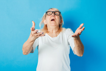 Old lady with glasses catches any object on a blue background