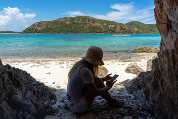 Woman using smartphone on sand beach under shade