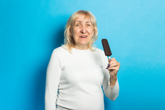 Old Lady Eating Ice Cream On A Blue Background. Concept Summertime, Summer, Heat