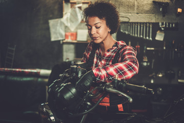 Fototapeta na wymiar African american woman mechanic repairing a motorcycle in a workshop