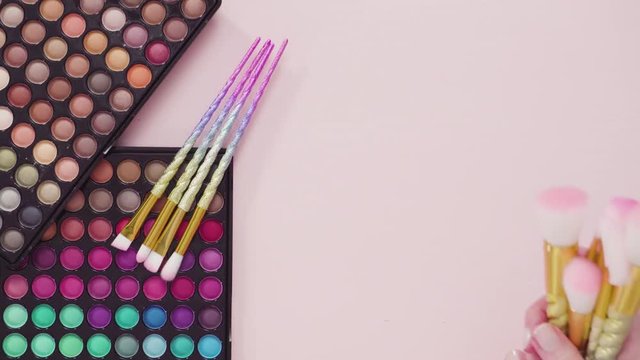 Flat lay. New eyeshadow palette with makeup brushes on a pink background.