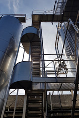 Naklejka premium Stairway to the sky between metal structures and tanks..