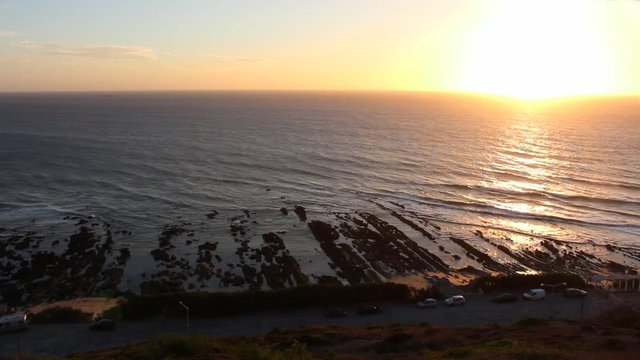 Gentle Ocean waves on rocky shore during the sunset, seen from a viewpoint in Cabo Mondego, in Portugal.
