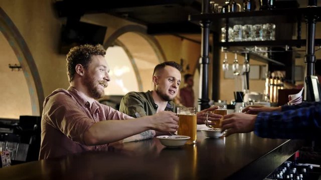 Cheerful friends drinking draught beer in a pub
