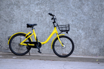 Yellow bicycle, black wheels parked on the wall.Vehicles with 2 wheels, driving with manpower.
