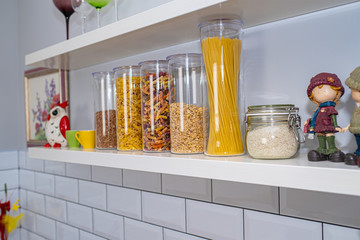 Various uncooked groceries in glass jars arranged on wooden shelves