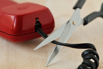 Scissors cutting telephone cord - Concept of landline phone