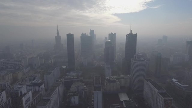 Aerial view of the tall buildings and skyscrapers of the city of Warsaw, at sunrise in the fog.