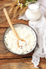 Fresh dairy products on background. Glass jar of milk, bowl of cottage cheese 