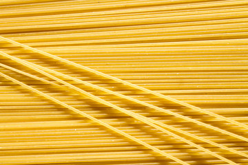 background of long raw yellow spaghetti pasta in horizontal plane, and some macaroni on top. 