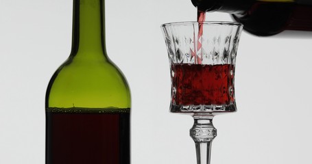 Rose wine. Red wine pour in wine glass over white background