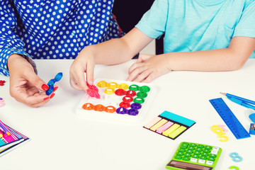Mother and kid plays logic game at table. Logical thinking training. Modern logic games. Workplace table with calculator, pens and notebooks. Education and development concept