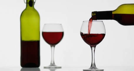 Rose wine. Red wine pour in wine glass over white background