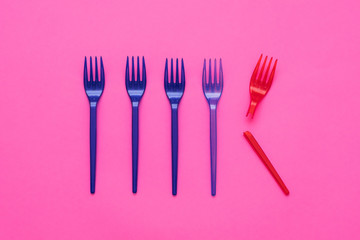 Plastic littering. Ecology problem. Multicolor disposable forks arranged over pink background.