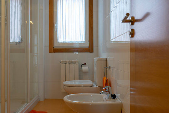 Close up of bathroom with decoration in orange and white colors, showing the well, the bidel and the shower