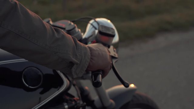 Motorcyclist sitting on his custom bike in sunrise