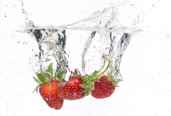 ripe red strawberries are thrown and dropped into sparkling water, many bubbles