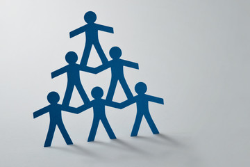 Human pyramid of paper cut-out people on white background - Concept of teamwork