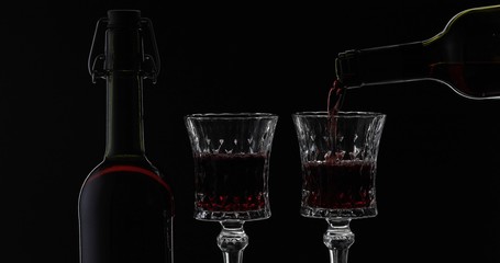 Fototapeta na wymiar Rose wine. Red wine pour in wine glass over black background. Silhouette