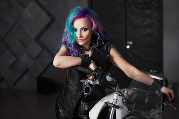 Cool girl in leather clothes near the motorcycle. Young stylish woman with colored hair on the bike.