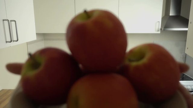 POV of attractive blonde hair young woman opens a cupboard and puts plate with apples from a shelf. Kitchen entourage.
